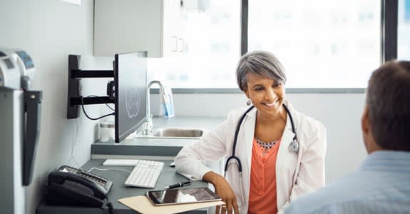 A doctor smiles and speaks with her patient