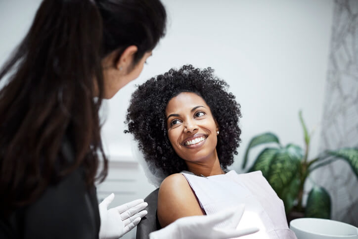 Woman smiles at her dentist while sitting in dentist chair