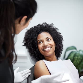 Woman smiles at her dentist while sitting in dentist chair