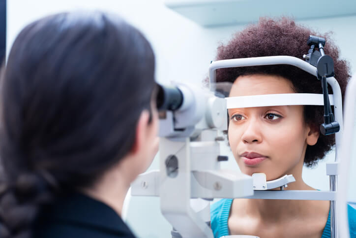 A woman looks into equipment while getting an eye exam