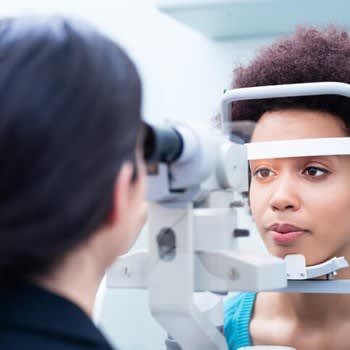 A woman looks into equipment while getting an eye exam