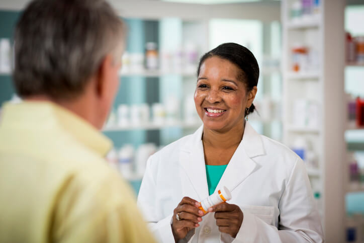 Pharmacist holds prescription for patient and smiles