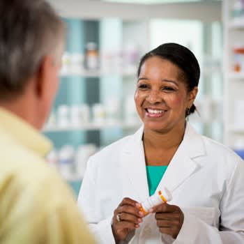 Pharmacist holds prescription for patient and smiles