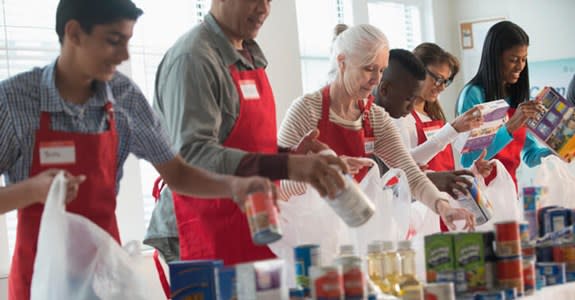 Volunteer workers pack food into bags to distribute