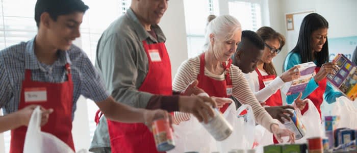 Volunteer workers pack food into bags to distribute