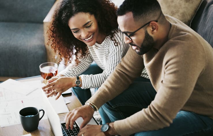 Young couple uses a laptop computer at home on coffee table