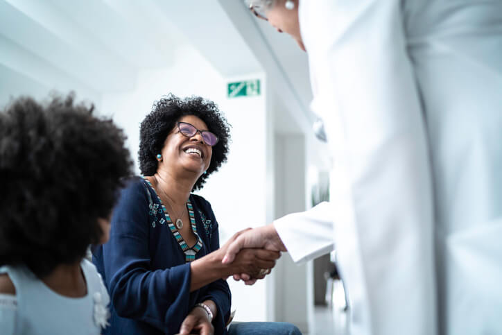 Woman smiles and shakes hands with her doctor at doctor's office
