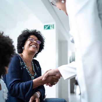 Woman smiles and shakes hands with her doctor at doctor's office