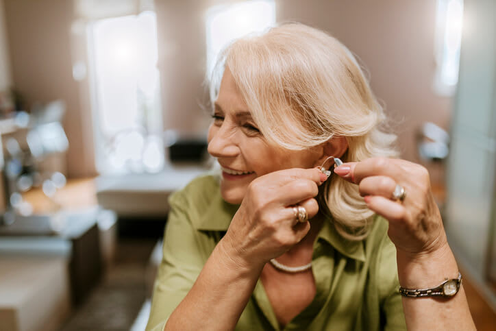 Woman smiles and fits on her hearing aids