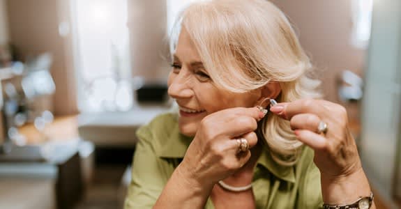 Woman smiles and fits on her hearing aids