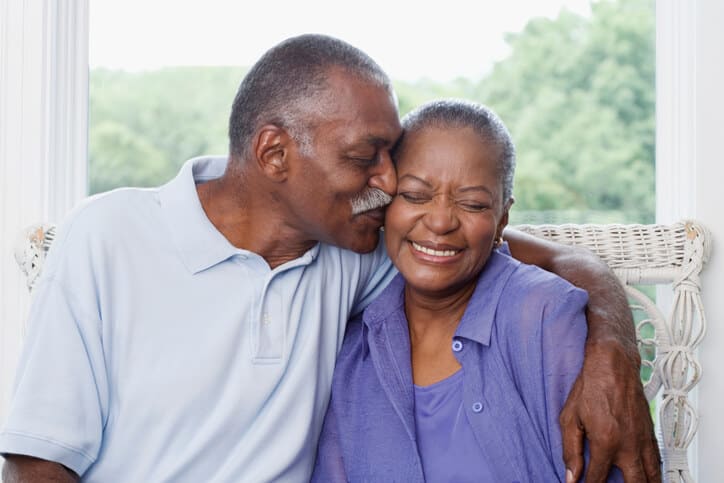 Man kisses his smiling wife on her cheek