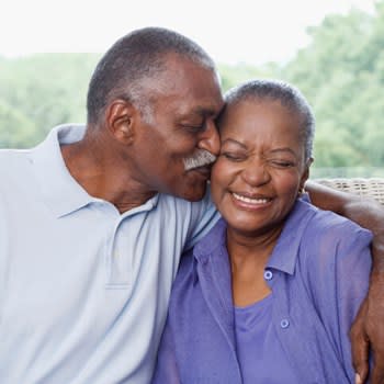 Man kisses his smiling wife on her cheek