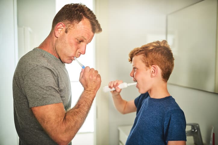 Father and son brushing teeth in bathroom