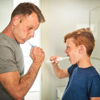 Father and son brushing teeth in bathroom