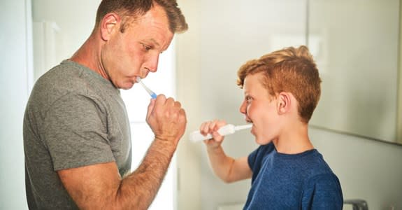 Father and son brushing teeth in bathroom