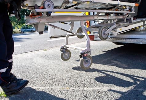 A view of the bottom of a medical gurney being loaded into the back of an ambulance