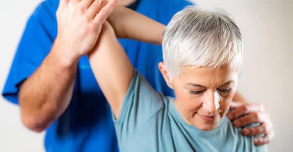 A chiropractor pulls a woman's arm back in a stretch