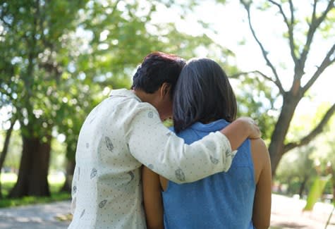 Rear view of two women comforting each other with embrace