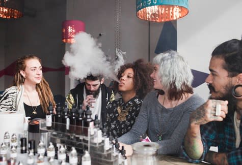 A group of young adults vaping and using e-cigarettes in a vape store