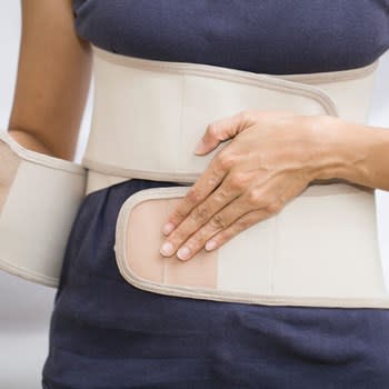 Front view of woman buckling a back brace