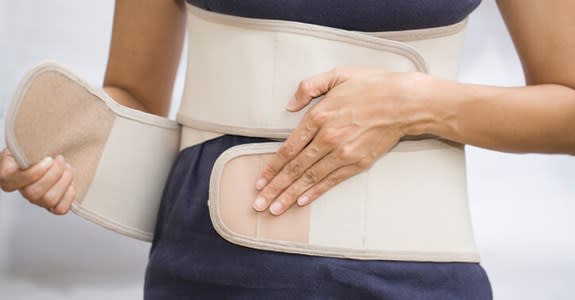 Front view of woman buckling a back brace