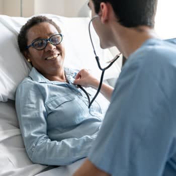 Smiling woman in hospital bed attended by nurse