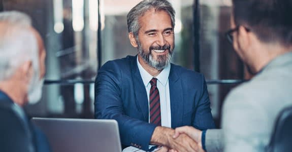 Man smiles and shakes hands with potential employer job interviewer