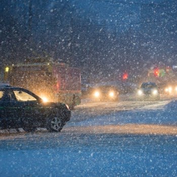 A snowy night scene with car headlights