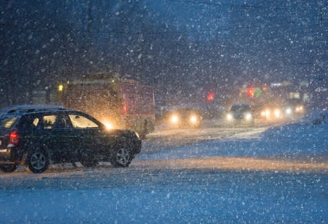 A snowy night scene with car headlights