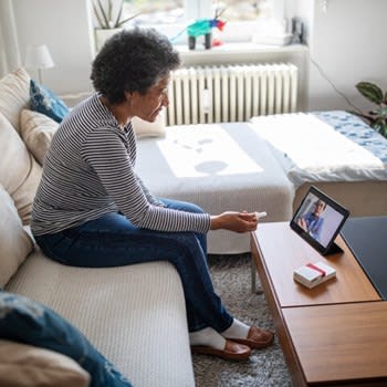 Woman at home speaks with doctor using telemedicine