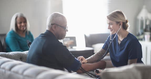 Home health nurse measures patient's blood pressure