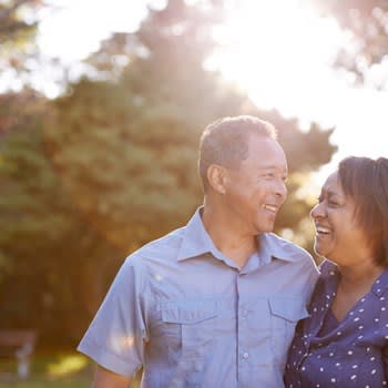 Smiling couple outdoors with sun in the background