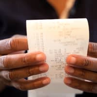 Two hands holding a receipt showing grocery prices