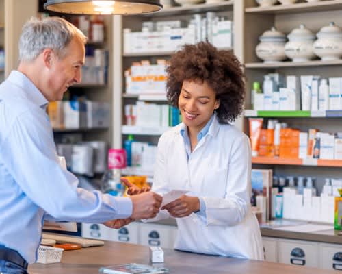 Pharmacist gives prescription to patient at drug store