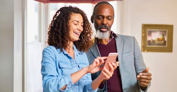 A couple smile while she uses her smart phone