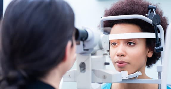 A woman looks into equipment while getting an eye exam
