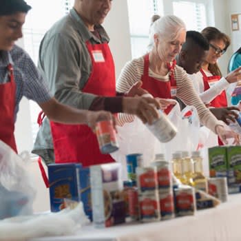 Volunteer workers pack food into bags to distribute