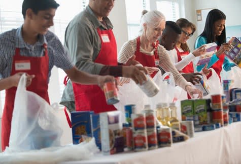 Volunteer workers pack food into bags to distribute