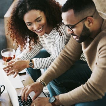 Young couple uses a laptop computer at home on coffee table