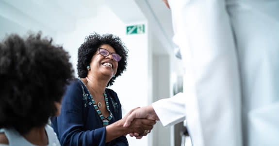 Woman smiles and shakes hands with her doctor at doctor's office