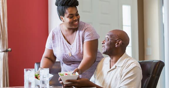 Family caregiver serves lunch to her father