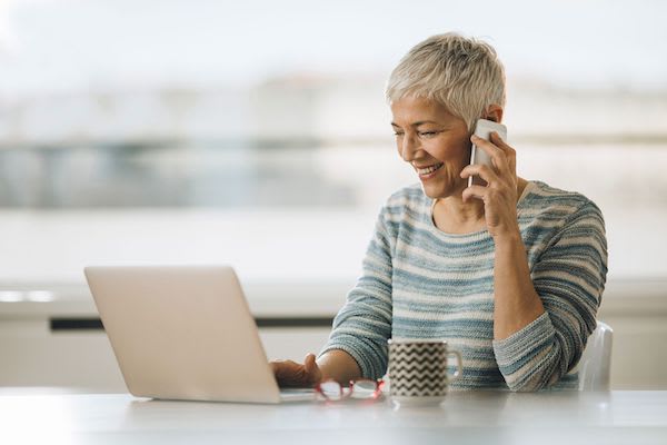 Woman on her phone while using laptop computer