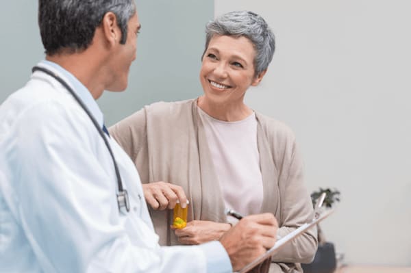 Woman smiles as doctor gives prescription