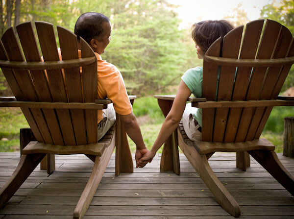 Couple holding hands sitting in chairs outdoors