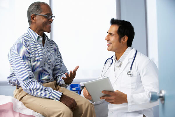 Patient and doctor smiling and talking in doctors office