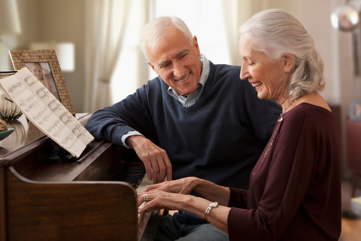 Couple sits at piano while wife plays