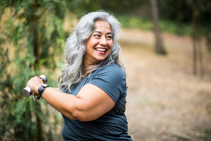 Woman exercises outdoors with dumbbell weights