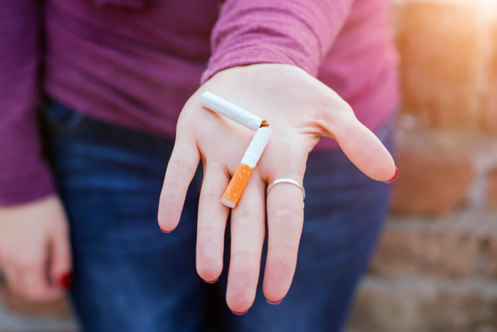 A woman holds a broken cigarette because she has quit smoking