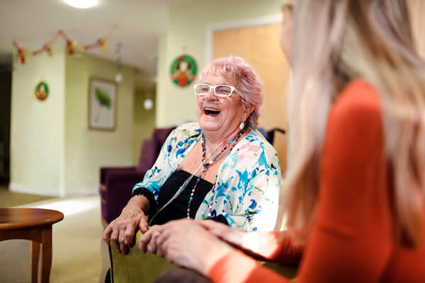 Woman laughs with friends while using oxygen tank and tubes
