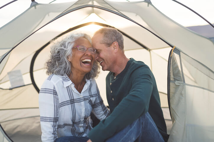Couple laughs and snuggles in a camping tent